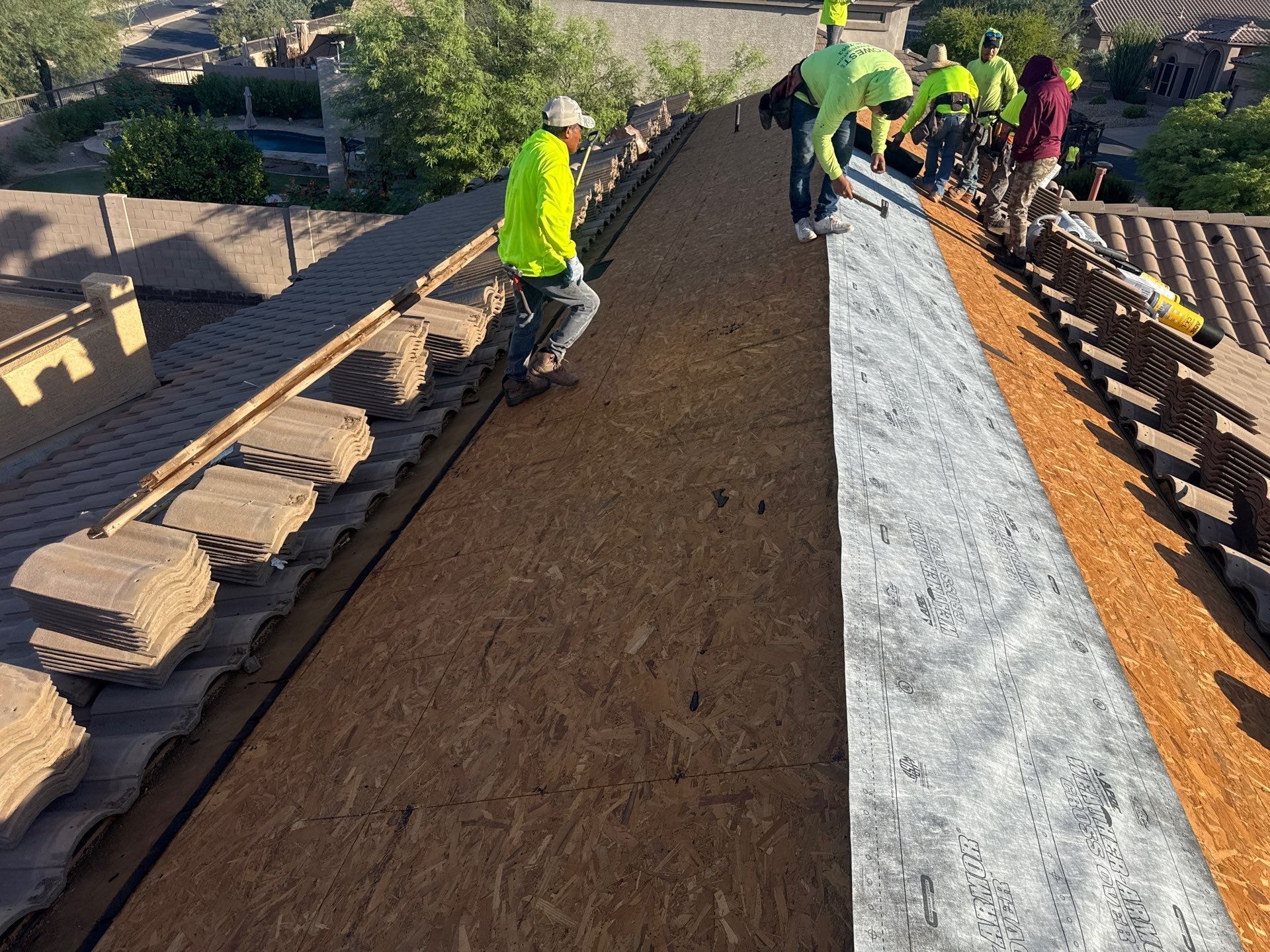 APM Builders crew rolling out underlayment on tile roof